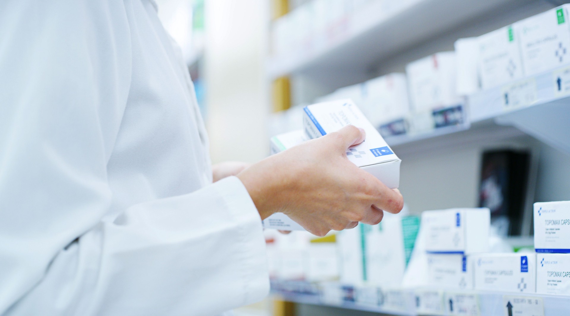 Doctor, hands or shelf with medication at pharmacy for inventory, stock or pharmaceutical service. Closeup, healthcare employee or pharmacist with box or medical product for side effect at drug store